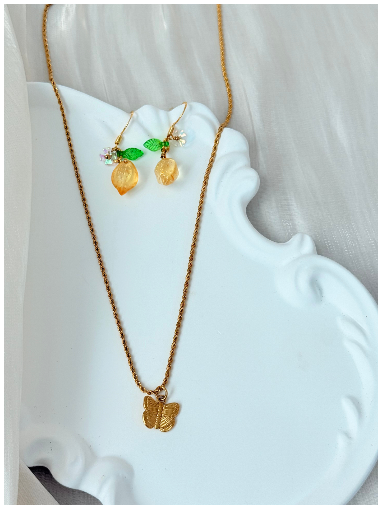Gold necklace and earrings on a white decorative stand