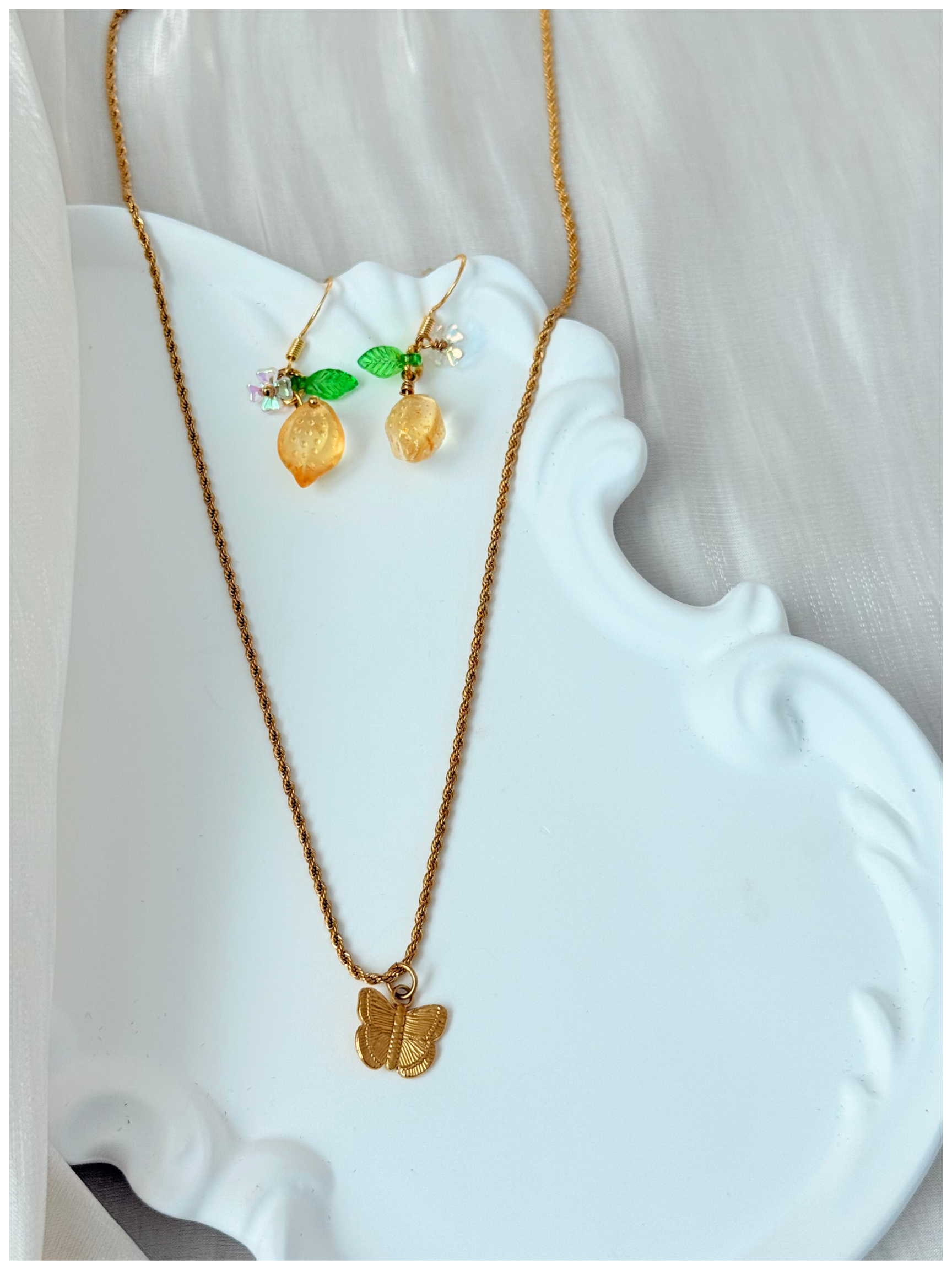 Gold necklace and earrings on a white decorative stand