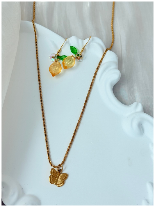Gold necklace with butterfly pendant on a white decorative object