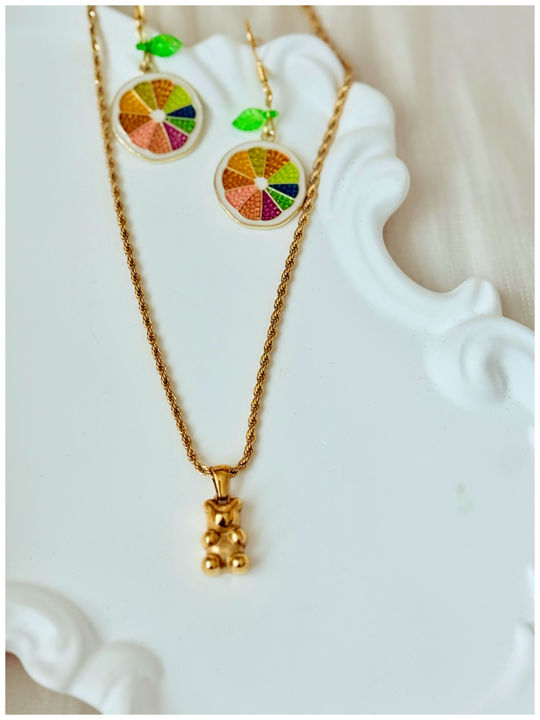 Gold necklace with colorful pendant on a decorative white surface