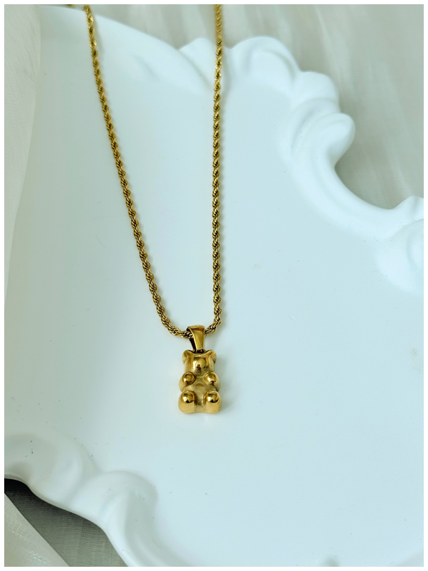 Gold necklace with a bear pendant on a white stand